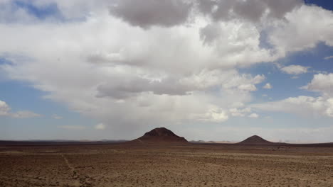 A-vast-barren-and-desolate-desert-landscape-with-two-cone-shaped-extinct-volcanic-mountains---aerial-parallax-view