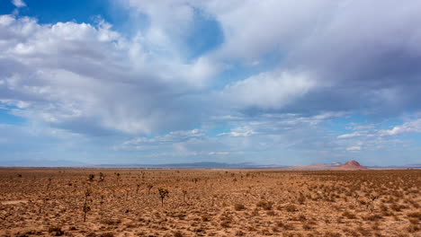 Ein-Sich-Schnell-Bewegender-Luft-Hyper-Lapse-über-Die-Mojave-Wüste,-Joshua-Bäume-Und-Ein-Flaches-Becken-Mit-Bergen-In-Der-Ferne