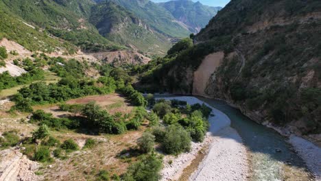 River-streaming-through-narrow-valley-between-mountains-and-lush-vegetation-in-Albania