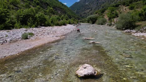 Scientist-studying-fauna-on-riverbed-of-the-last-wild-river-in-Europe-Vjosa,-sustainable-environment
