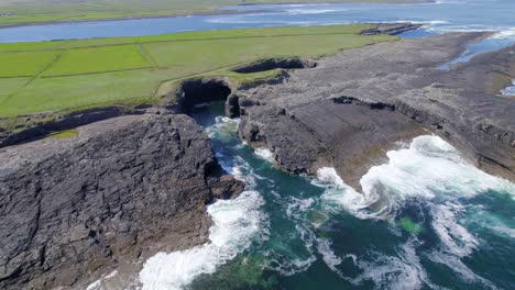 Aerial-reveal-shot-of-coastline-near-Bridge-of-Ross-rock-formation
