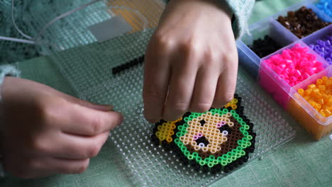 Closeup-Of-A-Female-Making-A-Colourful-Babushka-Design-From-Ironing-Beads
