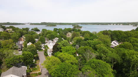 Aerial-footage-of-coastal-community-at-Hingham-MA,-showing-trees-in-full-summer-foliage,-drone-jib-down