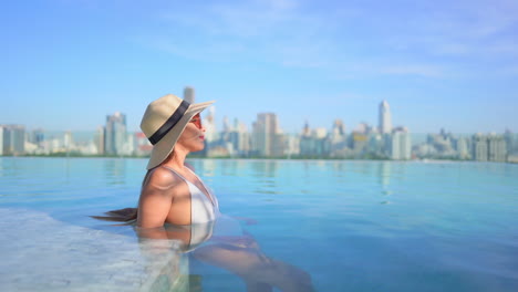 Sinnliche-Asiatin-Entspannt-Sich-Im-Luxuriösen-Infinity-Pool-Mit-Unglaublichem-Blick-Auf-Das-Stadtbild-Von-Bangkok-Im-Hintergrund