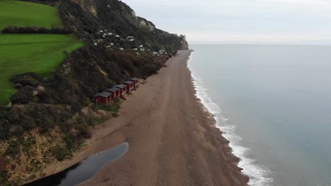 4K-Smooth-Aerial-shot-flying-above-the-oceans-edge-and-glimpsing-the-mountains-and-rolling-hills-of-Branscombe-Beach