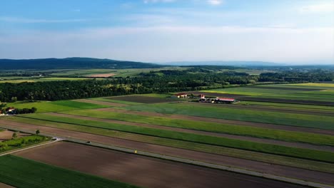 AERIAL---Agricuture-farm-fields,-Deutsch-Brodersdorf,-Austria,-wide-spinning-shot