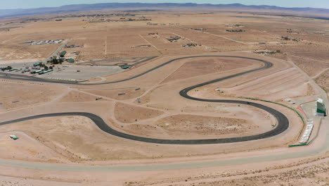 Cars-race-around-a-racetrack-located-in-the-Mojave-Desert---aerial-view-slow-motion