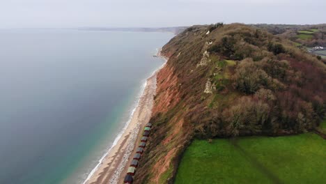 4K-Smooth-Aerial-shot-flying-high-above-the-Mountains-and-Rolling-Hills-of-UK's-Branscombe-Beach-and-glimpsing-the-beautiful-blue-ocean