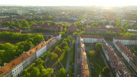 Aerial-forward-flight-over-residential-area-surrounded-by-green-nature-during-bright-sunset-in-Gdansk,Poland