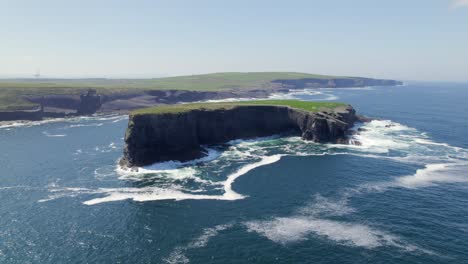Aerial-view-of-Illaunonearaun-islet-with-Kilkee-cliffs-and-wind-turbines-in-the-background