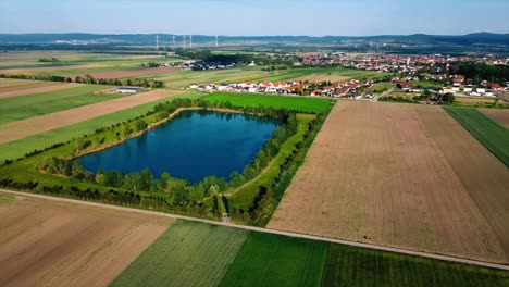 AERIAL---Reservoir-lake,-farm-fields,-Deutsch-Brodersdorf,-Austria,-circle-shot