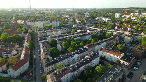 Aerial-fly-over-Gdansk-city-rooftops-and-clean-streets-with-parked-cars-near-buildings-sunset-from-high-point-of-view,-copy-space