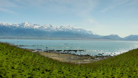 Toma-Panorámica-De-Montañas-Cubiertas-De-Nieve-De-Nueva-Zelanda-Ubicadas-Cerca-Del-Océano-Tranquilo