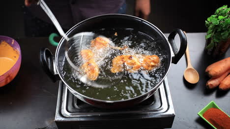 Chef-frying-chicken-lollipop-in-sizzling-hot-oil-with-a-help-of-stainless-steel-deep-fryer,-cooking-non-vegetarian-fast-food-at-home