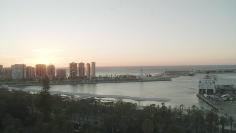 Luftaufnahme-Des-Hafens-Von-Malaga-Mit-Parkendem-Schiff-Und-Skyline-Während-Des-Epischen-Sonnenuntergangs-Im-Hintergrund