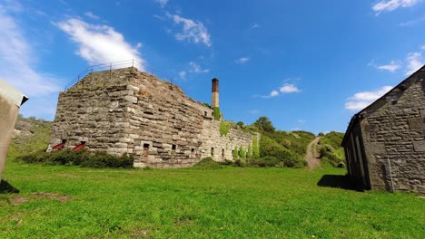 Old-abandoned-stone-industrial-mill-time-lapse-shadows-passing-countryside-grass-landscape-building-ruin