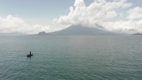 Man-on-small-boat-on-Atitlan-lake-and-surrounding-landscape,-Guatemala