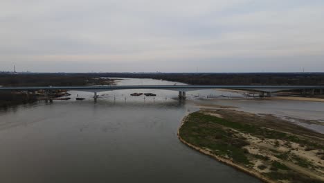 Dirt-and-Sand-floating-in-Vistula-River-after-finishing-build-of-new-modern-bridge,aerial-flight