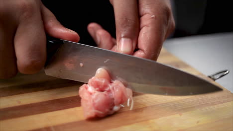 men-cutting-raw-chicken-wings-with-a-sharp-knife-and-shaping-into-a-lollipop-on-a-chopping-board-for-cook