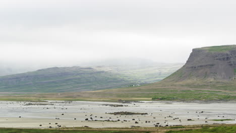 Swampy-low-lands-and-misty-mountains-on-horizon,-tilting-upward-view