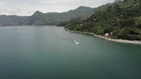 Aerial-drone-decending-view-of-motorboat-navigating-on-Atitlan-lake,-Guatemala