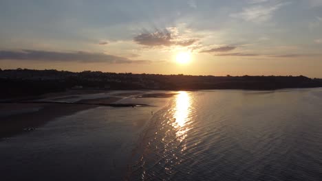 Sonnenuntergangsstrahlen-Strahlen-Feurige-Goldene-Farben-über-Den-Entspannenden-Strand,-Ozean,-Küste,-Luftbild,-Steigen-über-Wasser-Ab