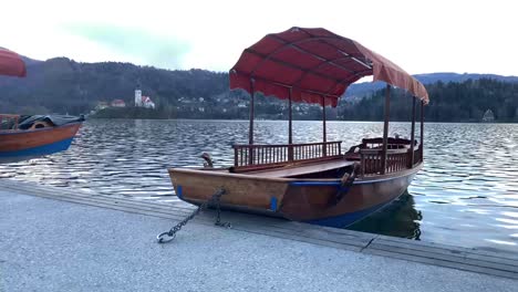 Typical-wooden-boats-called-"Pletna",-in-the-Lake-Bled-with-island-in-the-background