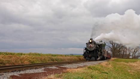 A-Low-Angle-of-a-Steam-Train-Puffing-Along-A-Rail-Road-Track-on-a-Windy-Day