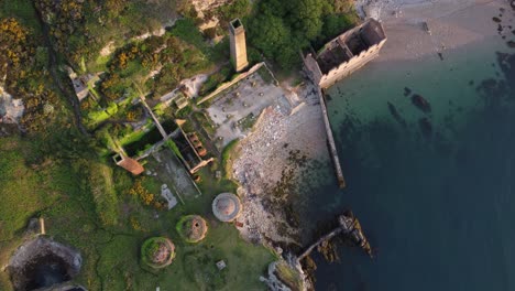 Porth-Wen-Verlassene-Verfallene-Mauerwerk-An-Der-Küste-Bleibt-Golden-Sonnenaufgang-Landschaft-Bucht-Luftaufnahme-Langsame-Spirale-Vogelperspektive