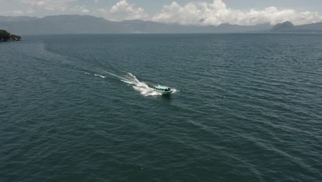 Passenger-boat-navigating-fast-toward-San-Pedro-volcano-on-Atitlan-lake,-Guatemala