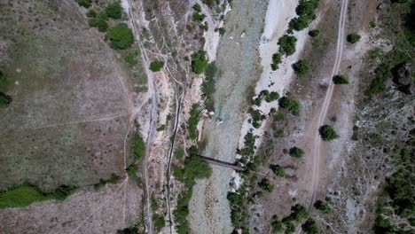 Riverbed-of-wild-river-branch-streaming-through-pebbles-seen-from-above-in-Albania