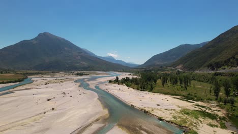 Paisaje-Fluvial-En-El-Valle-De-Vjosa,-Agua-Fluyendo-A-Través-Del-Lecho-Del-Río,-Fondo-De-Montañas