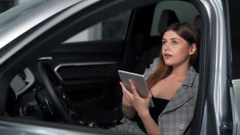 Beautiful-young-woman-receives-a-joyful-message-on-the-phone-while-sitting-in-the-car