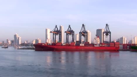 Harbor-cranes-moving-cargo,-with-red-ship-in-contrast-to-white-buildings