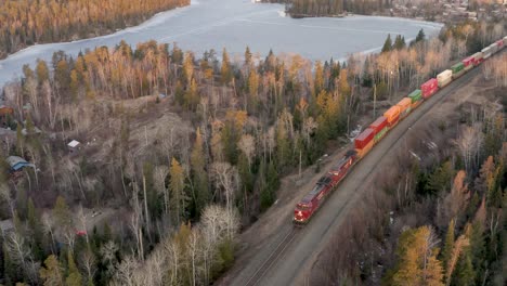 A-long-and-colorful-freight-train-pulling-a-large-number-of-shipping-and-cargo-containers-through-the-Canadian-shield