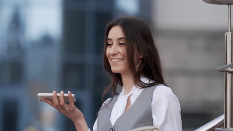 Happy-young-woman-in-business-clothes-talking-to-a-smartphone