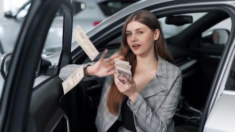 Stylish-young-woman-scattering-dollar-bills-while-sitting-in-the-car