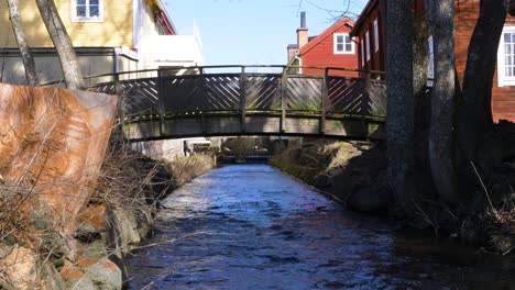 A-small-bridge-over-a-creek-in-the-town-of-Eksjö,-Sweden,-wide-shot