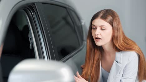 Stylish-young-woman-holds-her-hand-on-a-new-car
