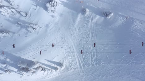 Ski-chairlift-on-winter-ski-slopes,-4K-aerial-top-down-view