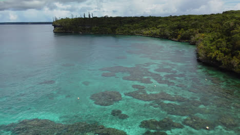 Low-aerial-flyover-of-natural-marine-reserve-Jinek's-Bay,-Lifou,-New-Caledonia
