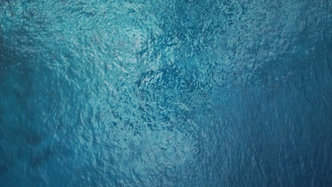 Aerial:-top-down-view-of-blue-ocean-surface,-turquoise-sea-water-background