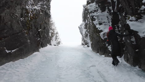 Girl-walking-on-ice-and-snow-in-a-big-cave-in-Björkliden,-Sweden