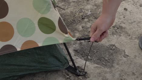 Outdoor-nature-woman-taking-pegs-out-of-ground-packing-up-tent