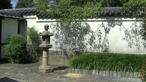 Paved-courtyard-of-a-Japanese-garden-with-tiled-wall-and-stone-lantern