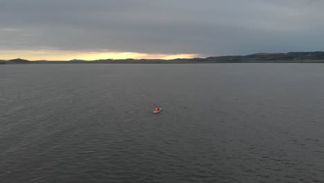 Aerial-orbit-around-with-an-orange-life-jacket-kayaking-on-lake-Victoria-with-the-sun-rising-on-the-horizon