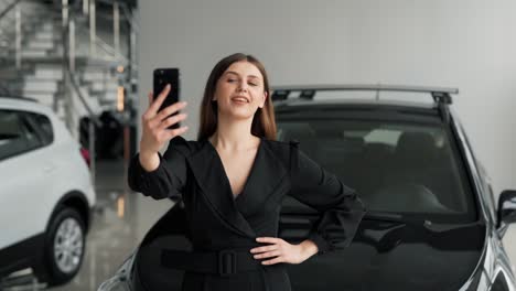Schöne-Junge-Frau,-Die-Ein-Selfie-Auf-Dem-Hintergrund-Eines-Neuen-Autos-In-Einem-Autohaus-Macht