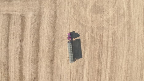 Big-semi-truck-leaves-field-with-harvested-grain,-tracking-drone-shot