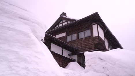 Eingeschneites-Holzgebäude-Mit-Hohen-Schneewänden,-Die-Es-Umgeben