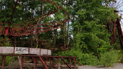 Abandoned-swing-ride-spinning-on-windy-day-in-Pripyat,-zoom-out-view